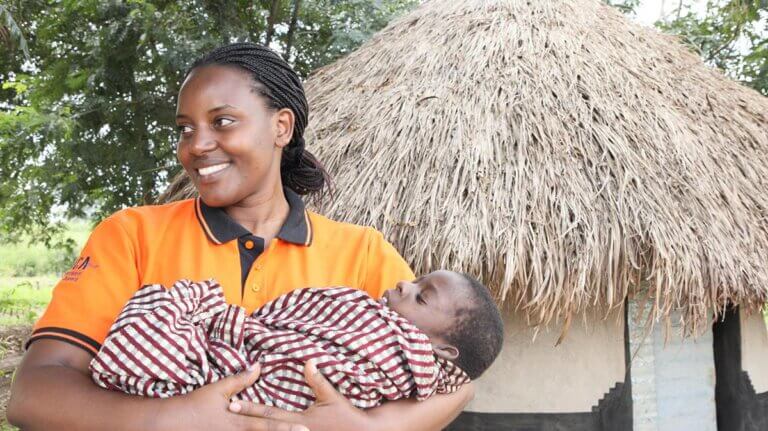 Ingrid Natukunda, a ‘Health and Nutrition for All’ project officer carries baby Gift.