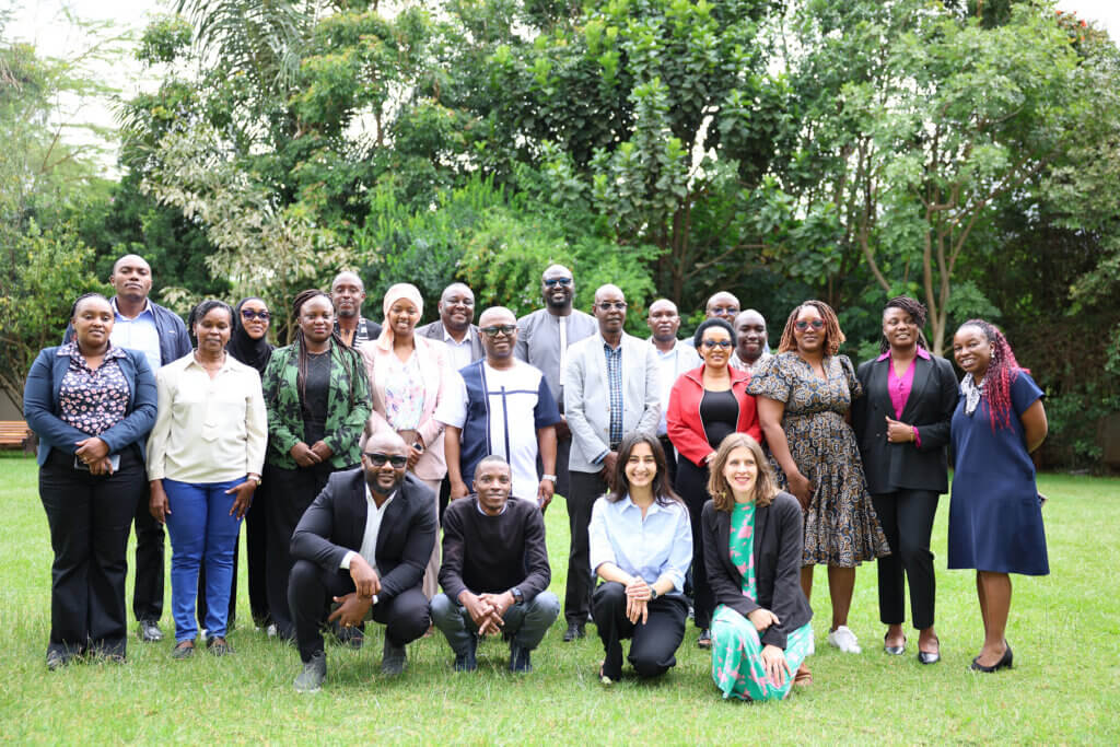 A diverse group of health and development professionals pose together outdoors following a fellowship gathering.