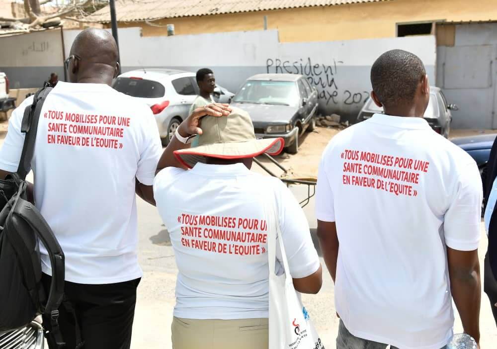 Community health advocates wearing campaign shirts walk through a neighbourhood as part of an equity-focused health initiative.